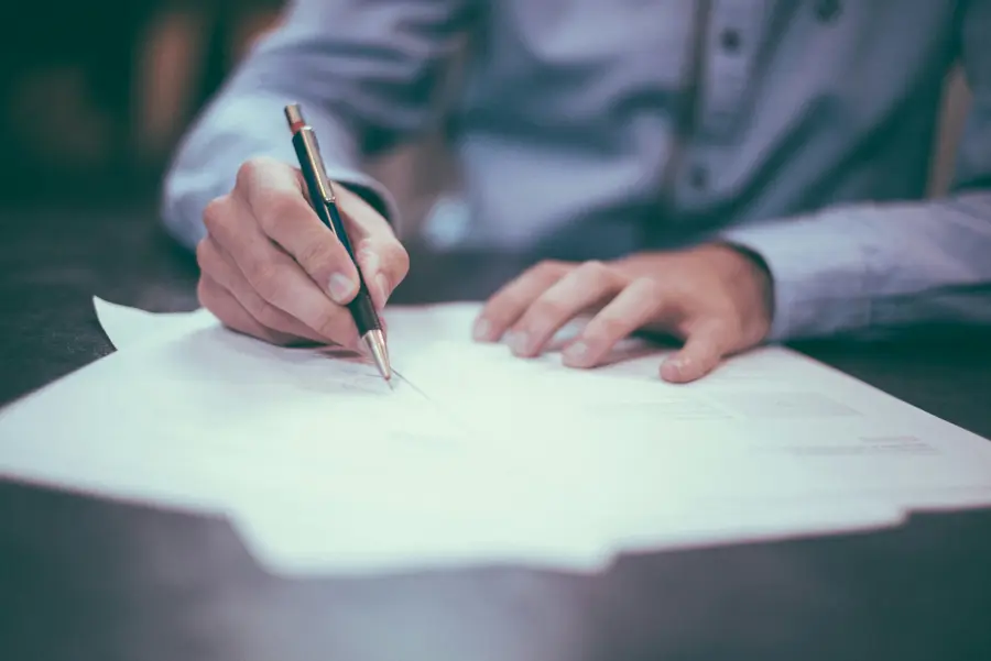 Person signing a document at a desk