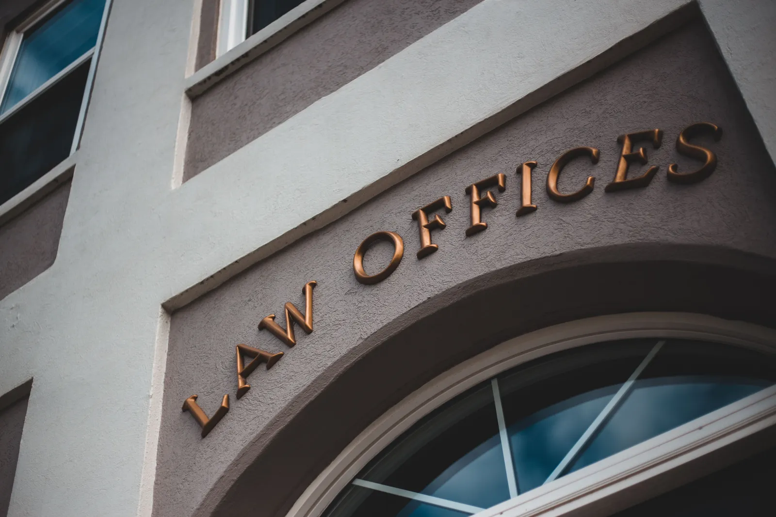 Bronze “Law Offices” lettering above an arched window on a building facade